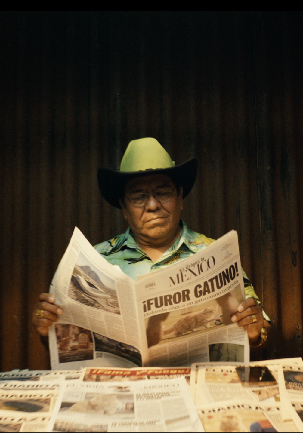 A man in a green cowboy hat reading a Mexican newspaper with the headline about the Dutch cat craze